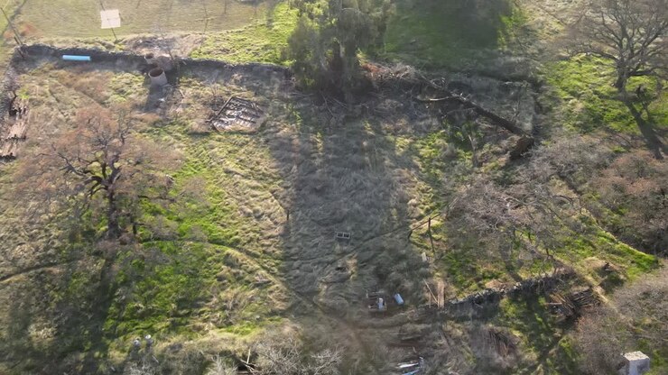 Drone footage over Clarksville, California on a bright sunny morning, showing trees with long shadows and grassland with interweaving pathways and walking trails