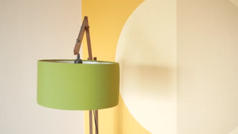 lámpara de piso verde contra una pared amarilla y beige