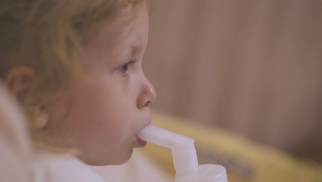 girl has procedure with plastic inhaler lying in soft bed