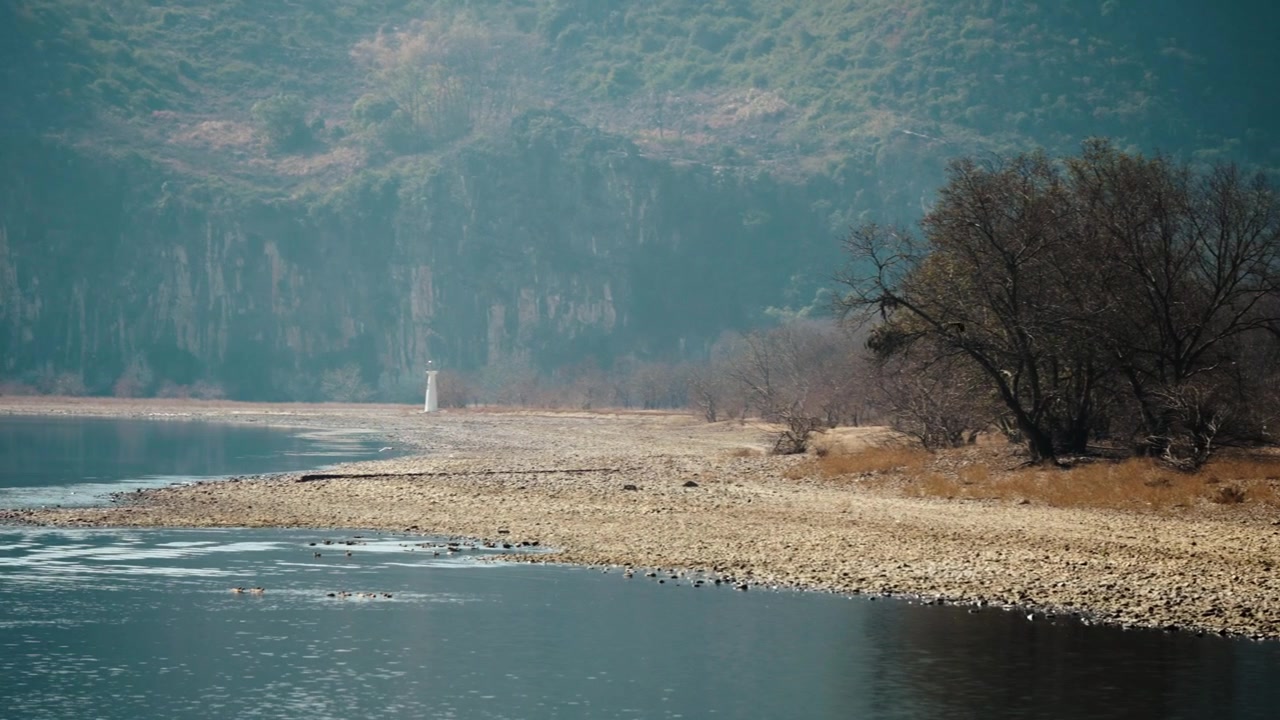 Yangshuo'da yükselen kireçtaşı karst kayalıklarının altından akan sakin nehir.