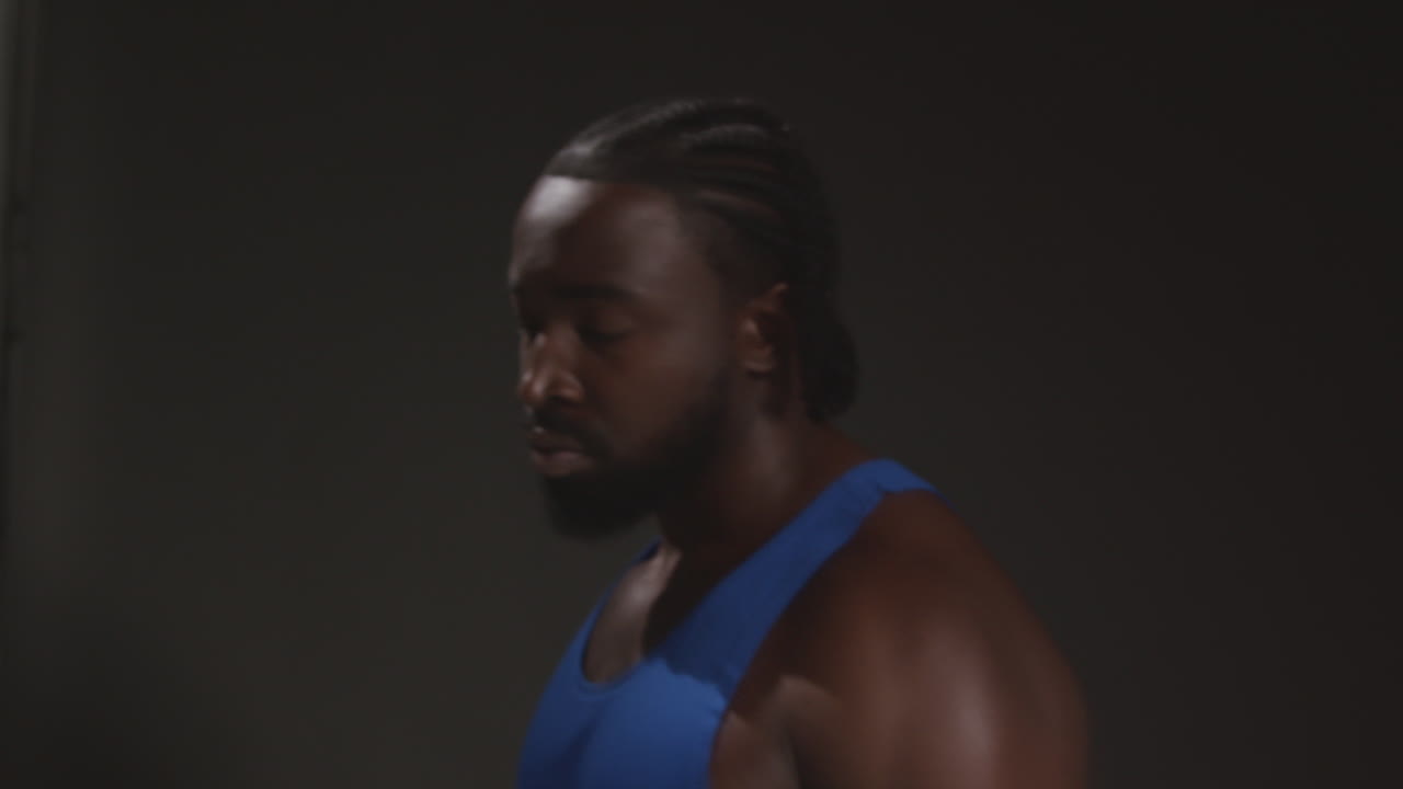 retrato en primer plano de un boxeador masculino serio con un chaleco alejándose del entrenamiento de la cámara para un evento deportivo contra un fondo de estudio negro