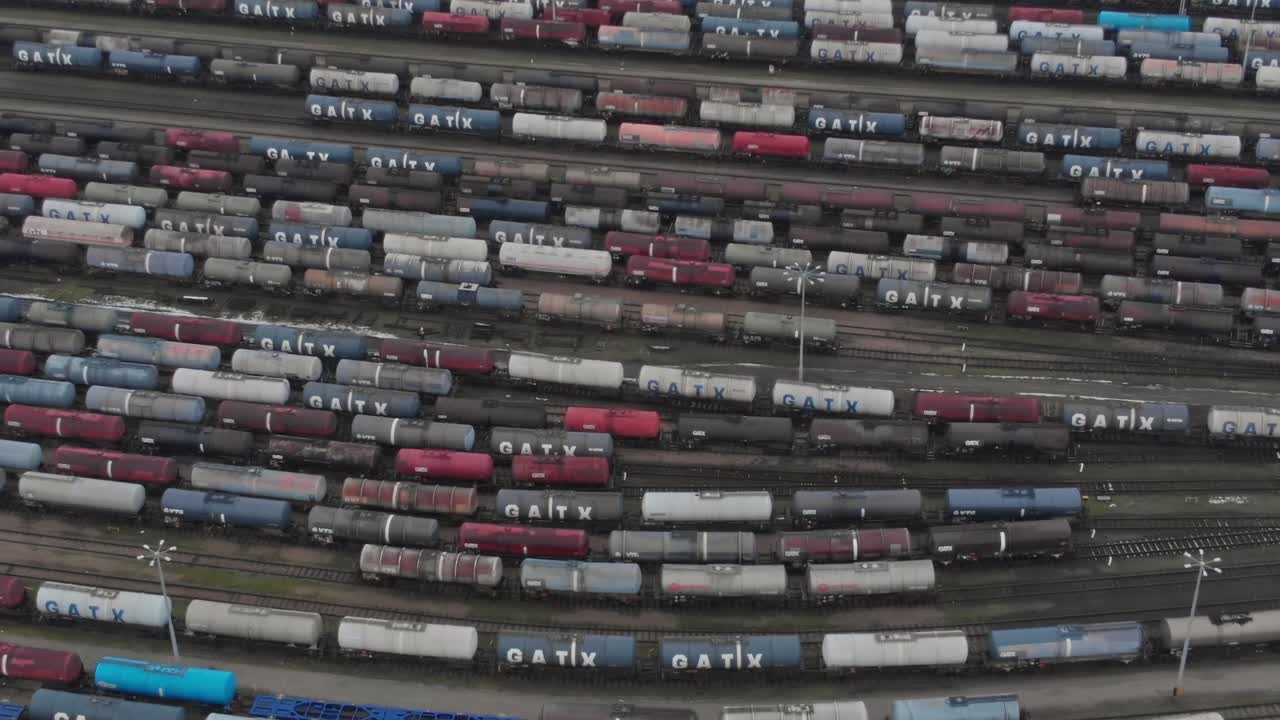 Trains lined up in a rail yard during daytime in an industrial area