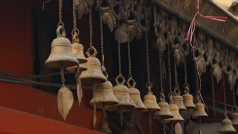 Row-of-hanging-brass-wind-bells-outside-temple-in-Kathmandu,-Nepal