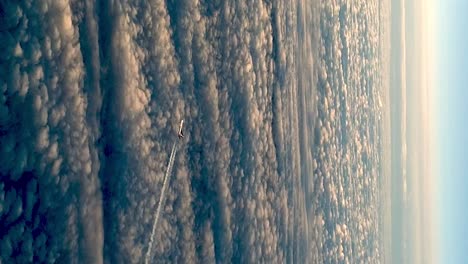 flying airplane above clouds leaving condensation vapor air trail in blue sky