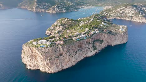 Aerial-view-of-limestone-cliff-with-villa-resorts-near-blue-water-bay,-Spain