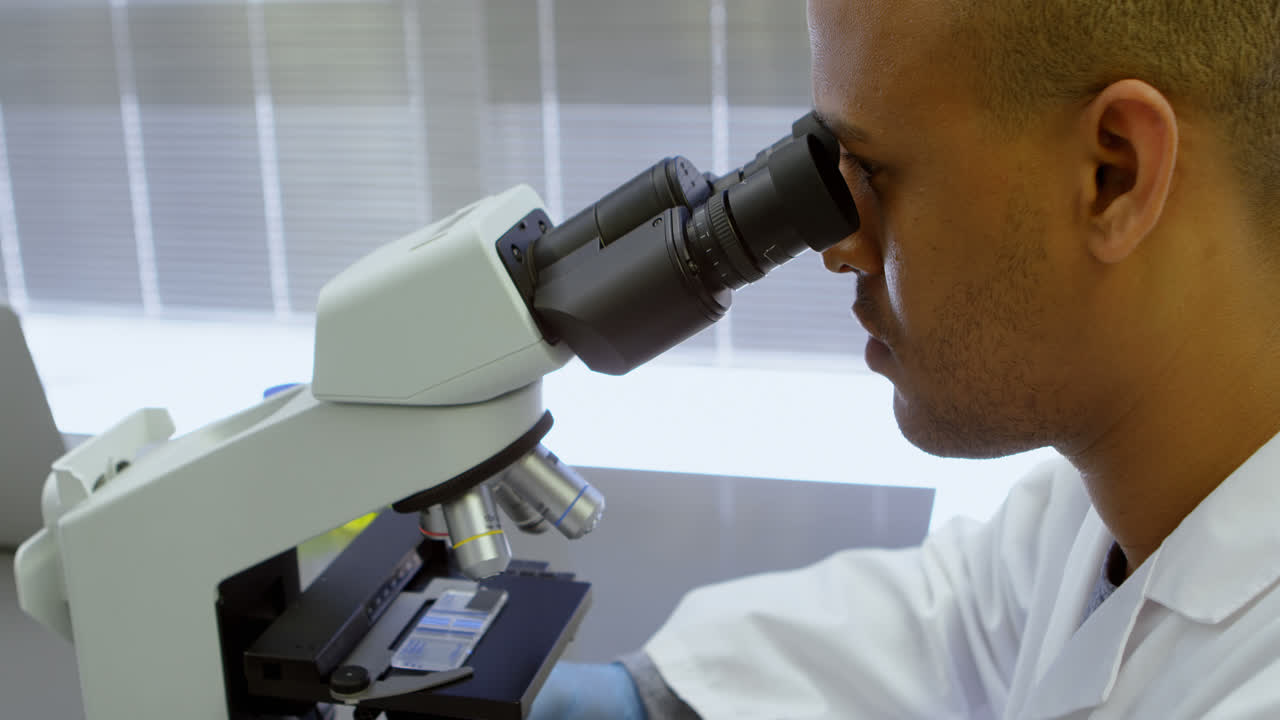 científico mirando a través del microscopio 4k