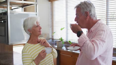 Pareja-Caucásica-Mayor-Hablando-Entre-Sí-Mientras-Toman-Café-Juntos-En-La-Cocina-De-Casa