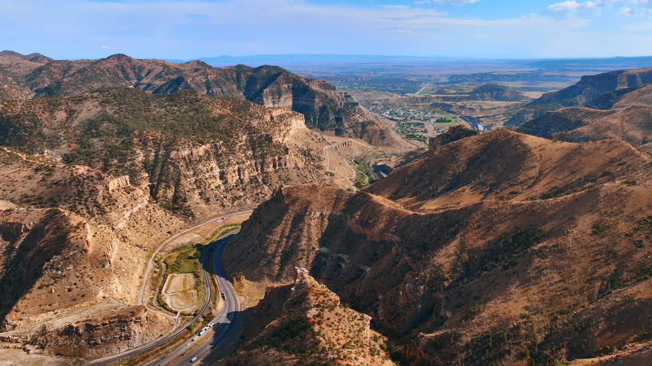 Drone view of Price Canyon in Utah with winding road and layered mountain cliffs under a bright sky