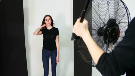 photographer holding fan for female model during photo shoot