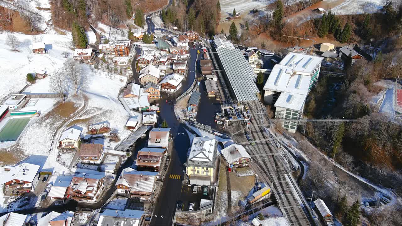 volando sobre un pueblo nevado hacia la estación de tren | lauterbrunnen suiza, valle suizo en los alpes dron, europa, 4k