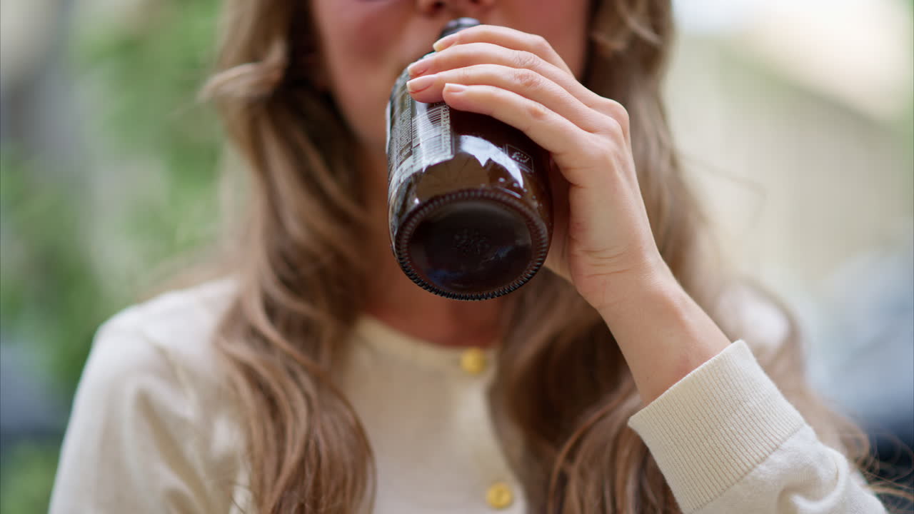 Primo piano di una giovane donna bruna che beve un tè kombucha all'aperto