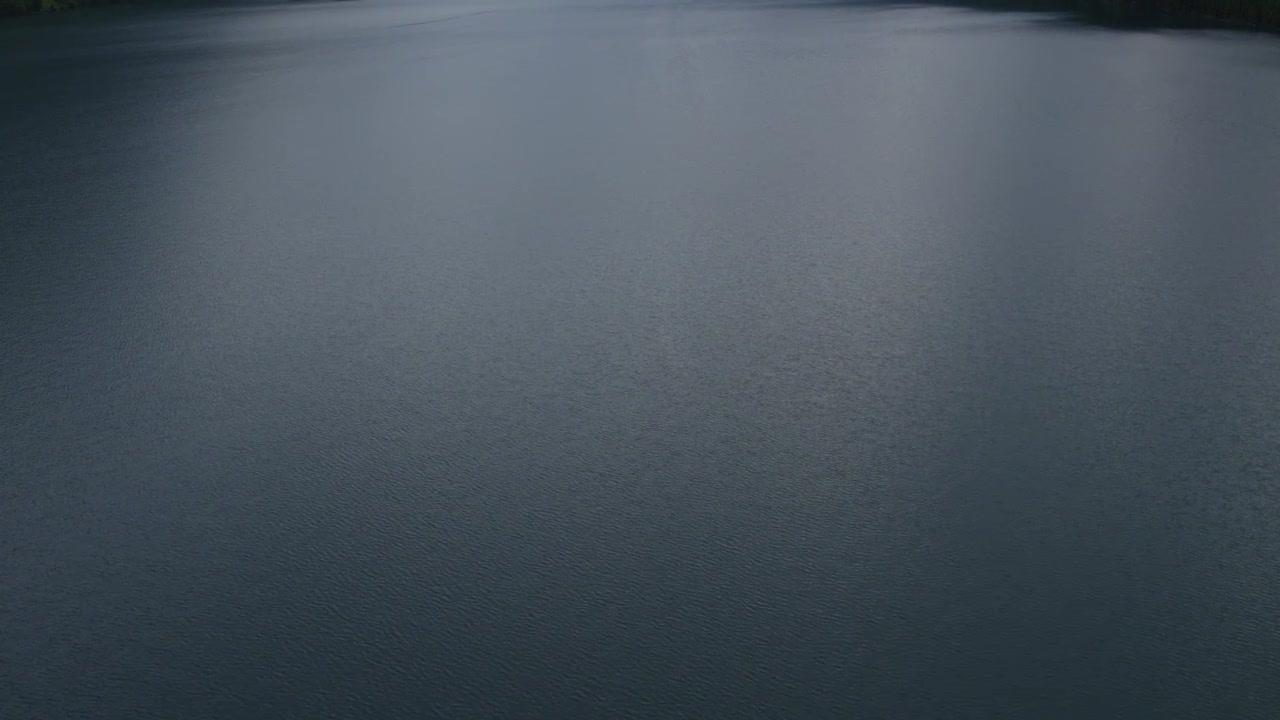 Droneoptagelser af en rolig søvandsoverflade med lette krusninger og bløde refleksioner, der skaber en minimalistisk naturbaggrund ved Multinskie-søerne, Altai-republikken, Rusland.