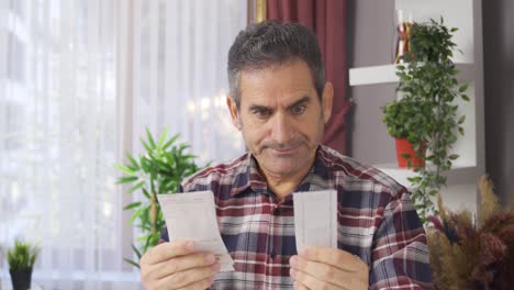 hombre en dificultades financieras mirando facturas y sintiéndose triste.