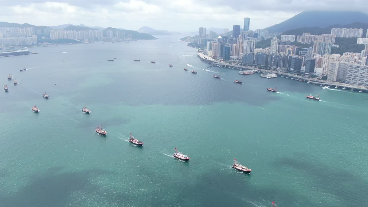 convoy de barcos de pesca locales que causan en la bahía victoria de hong kong, con el horizonte de la ciudad en el horizonte, vista aérea