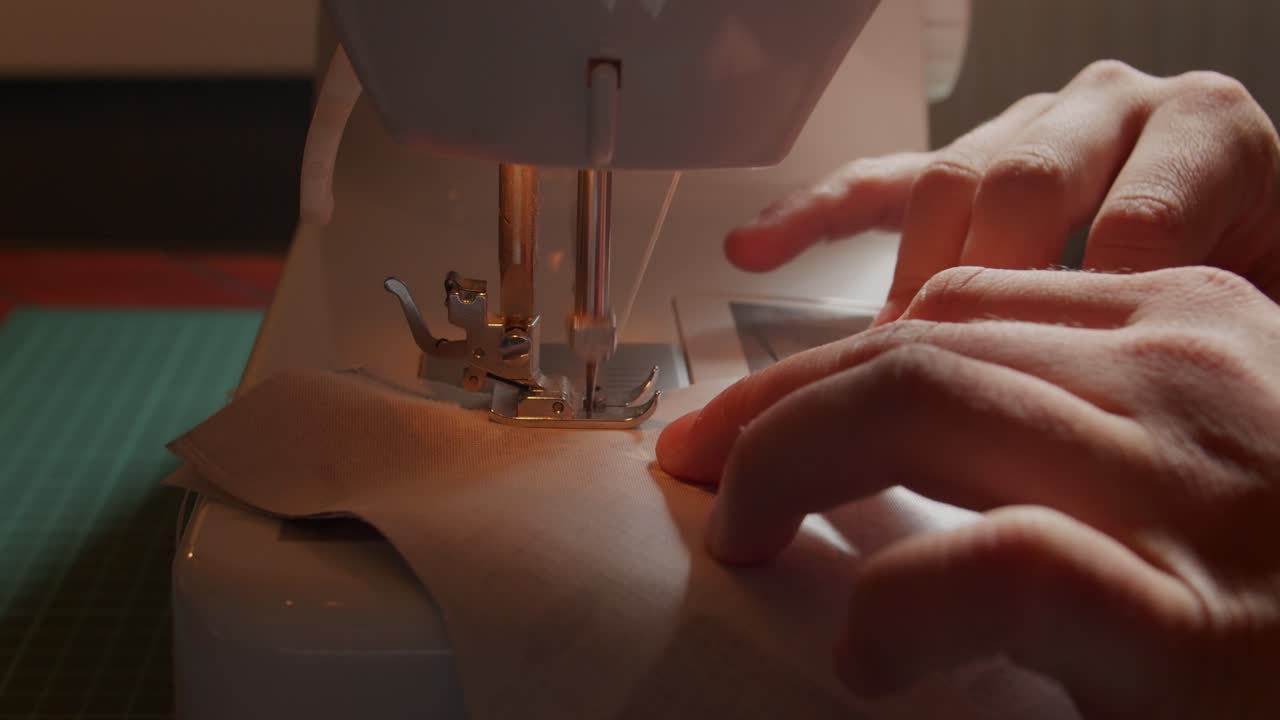 Close view from the side of sewing machine and operator working on fabric