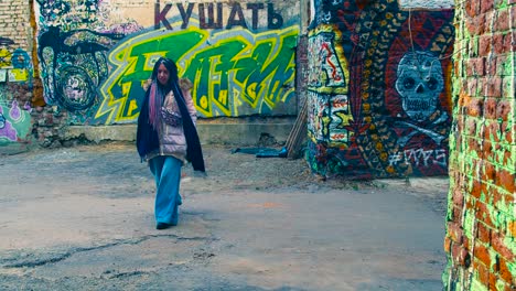 mujer caminando por un callejón cubierto de graffiti