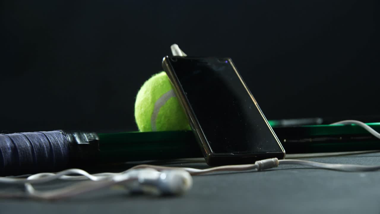 Palline da tennis, racchetta e smartphone con cuffie in studio 4k
