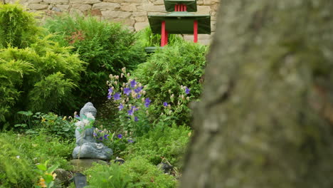 slide-shot-around-tree-reveals-zen-garden-with-buddha-statue-and-Chinese-temple