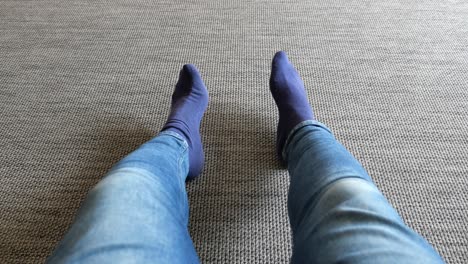 person wearing blue jeans and blue socks sitting on a carpet floor