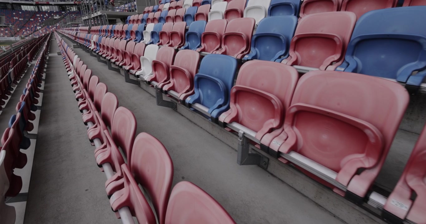 Gradas vacías en un estadio de fútbol moderno con asientos rojos, azules y blancos en Silesia, Polonia, toma dinámica en 4K