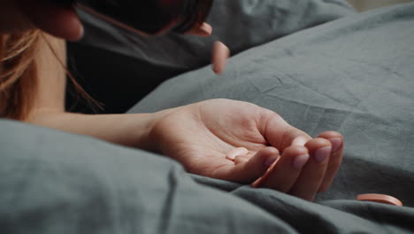 mujer tomando pastillas en la cama