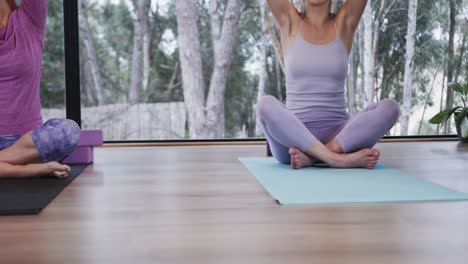 focused diverse women meditating together on mats in yoga class, slow motion