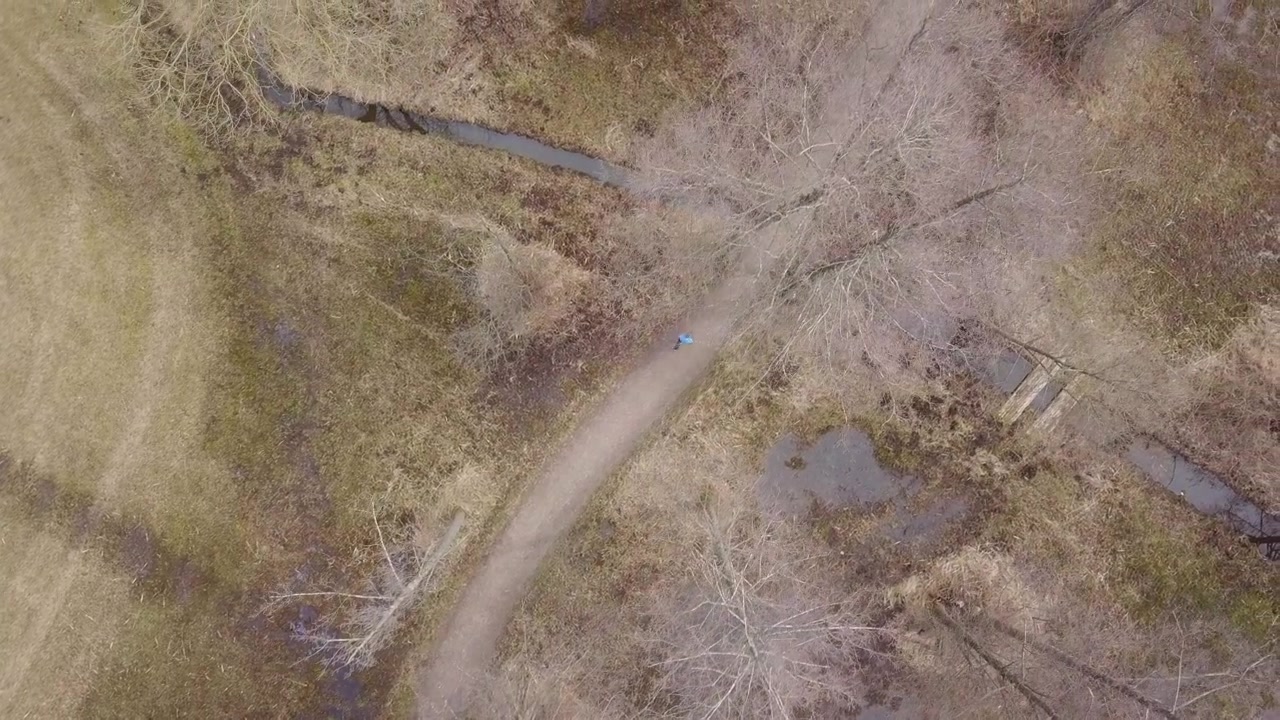 Drone shot of a man walking on a path through the countryside.