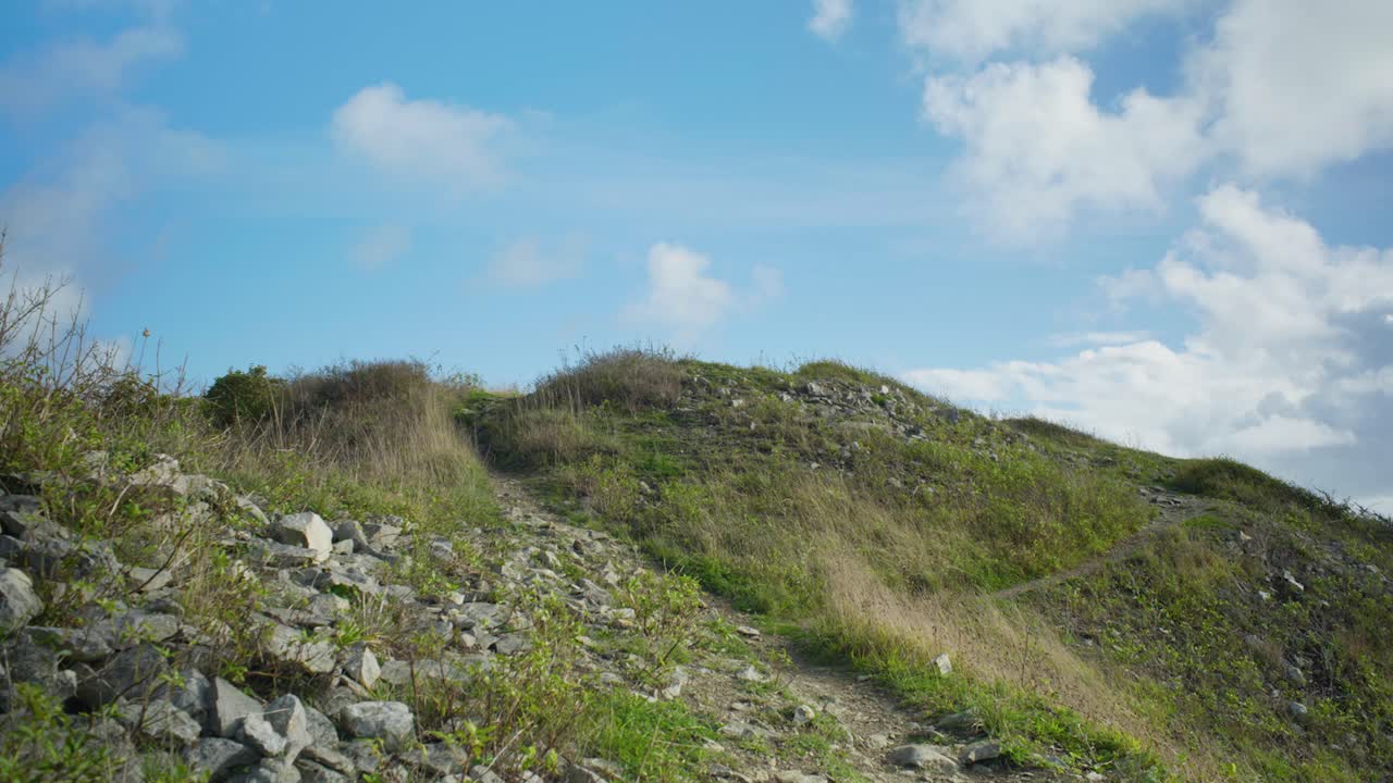 영국 도싯에 있는 포틀랜드 섬에서 화창한 날 절벽 가장자리로 올라가는 해안 산책로의 4k 시네마틱 샷