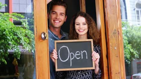 Portrait-of-couple-holding-open-sign-board