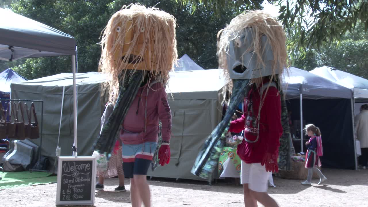 Teenagers wearing decorative masks and fancy dress stroll through a craft fair