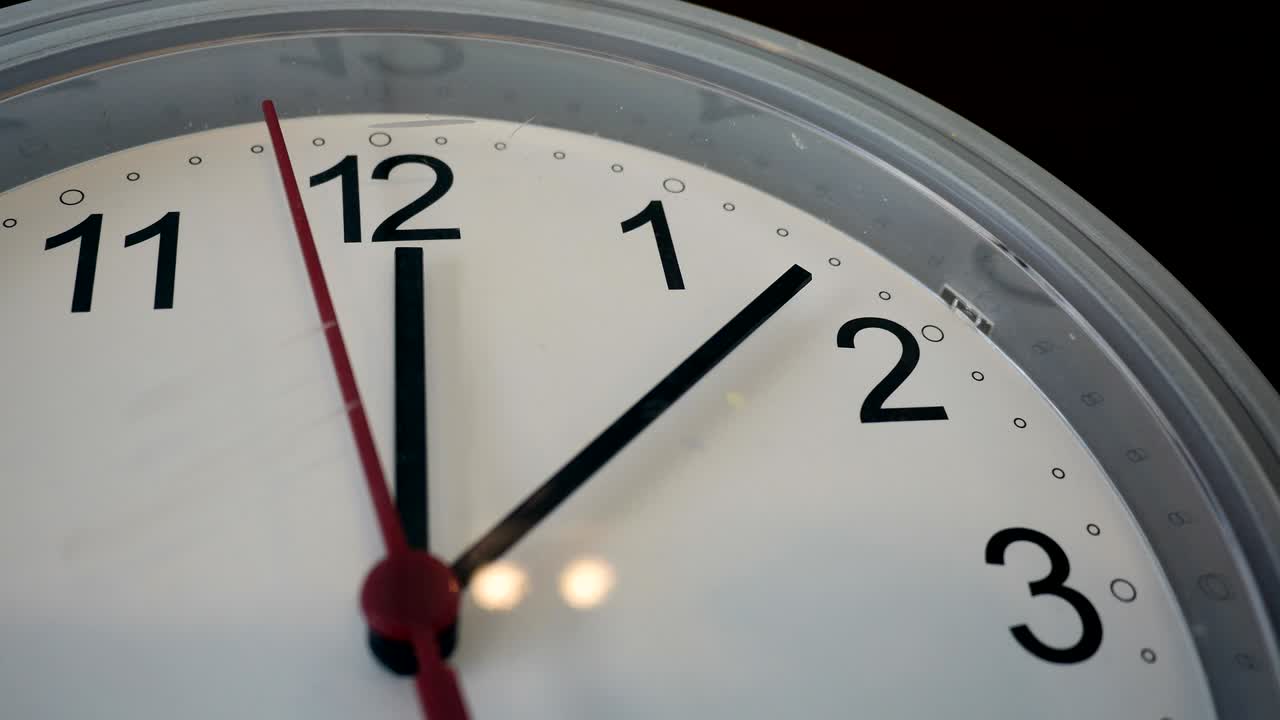 Wall clock with twelve oclock and a red ticking arrow. Professional shot in 4K resolution