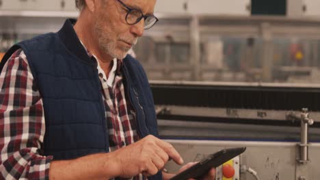 worker using digital tablet in bottle factory