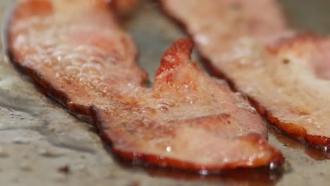 macro primer plano de tocino chisporroteando en la parrilla de un restaurante