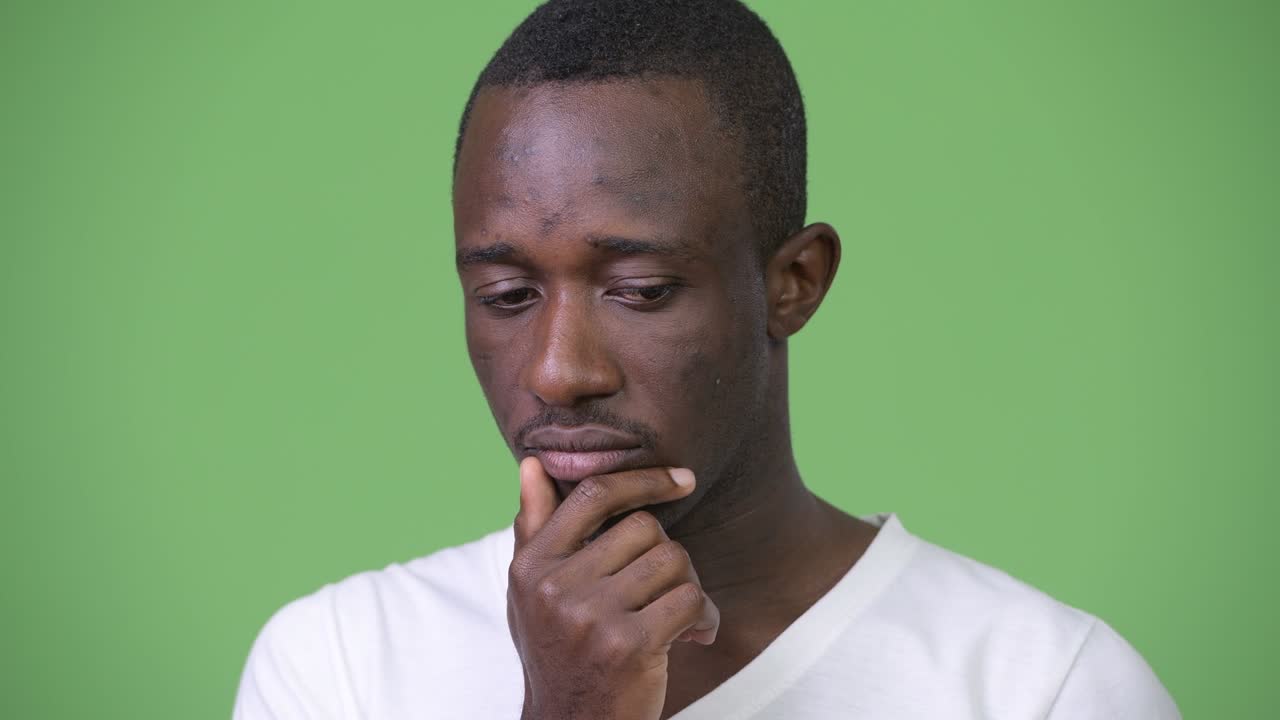 Young sad African man thinking and looking down