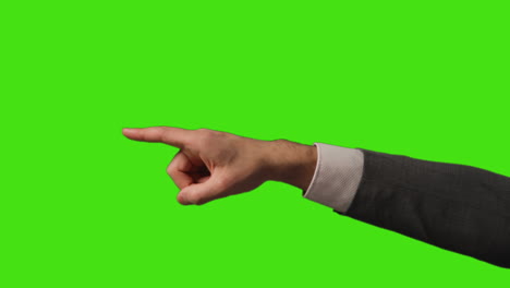 close up of businessman's hand pointing across frame against green screen showing direction or firing staff