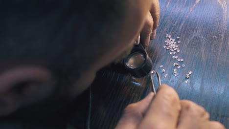 jeweler chooses diamonds looking through magnifying glass