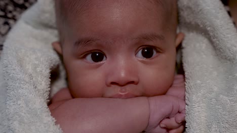 Adorable-Bebé-De-Dos-Meses-Envuelto-En-Una-Toalla-Chupando-El-Brazo