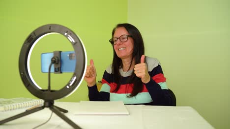 mujer usando un teléfono inteligente para una reunión de video en línea mostrando manos aprobadas - medio