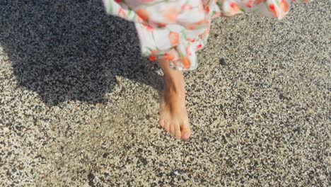 Girl in sundress on a vacation, walking on a beach with waves rinsing her feet