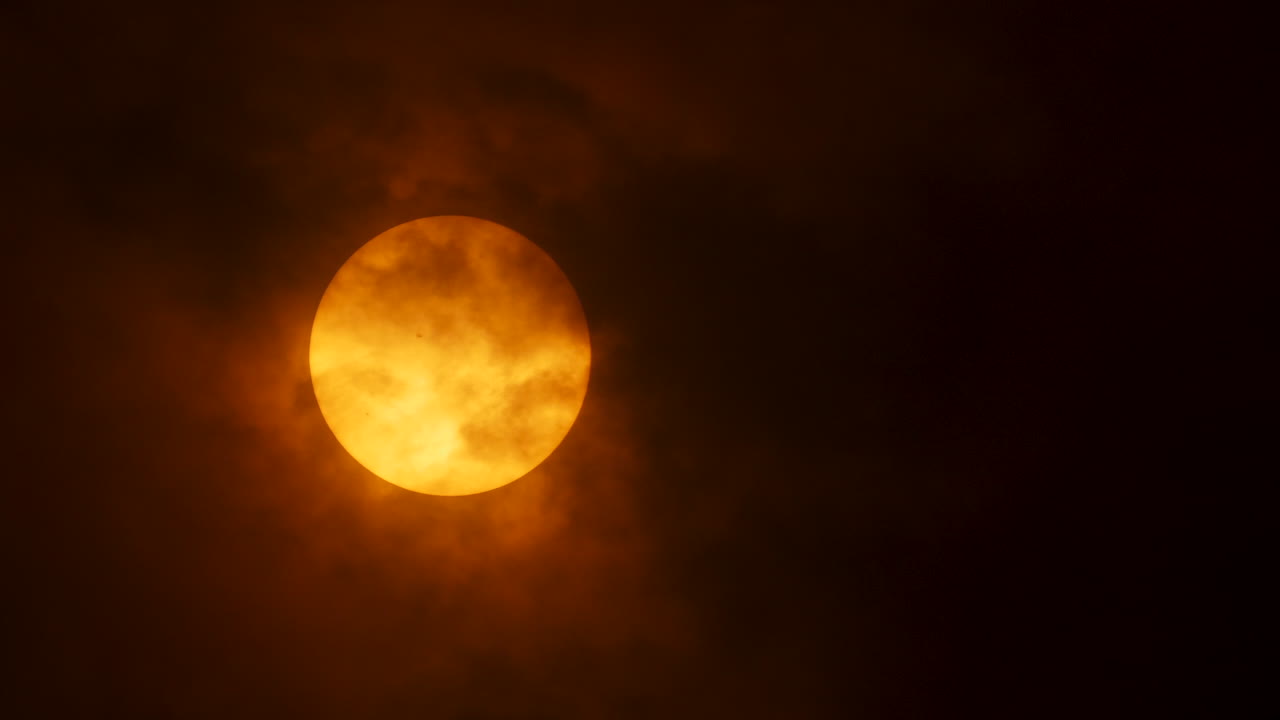 las nubes pasan sobre el sol en un día nublado, revelando una mancha solar