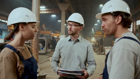 engineer giving instructions to two technicians in industrial plant