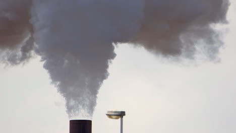 telephoto shot of smokestack emitting harmful greenhouse gases into atmosphere