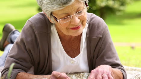 Senior-woman-relaxing-in-the-park-reading-a-book