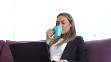 businesswoman working on laptop and drinking coffee at home