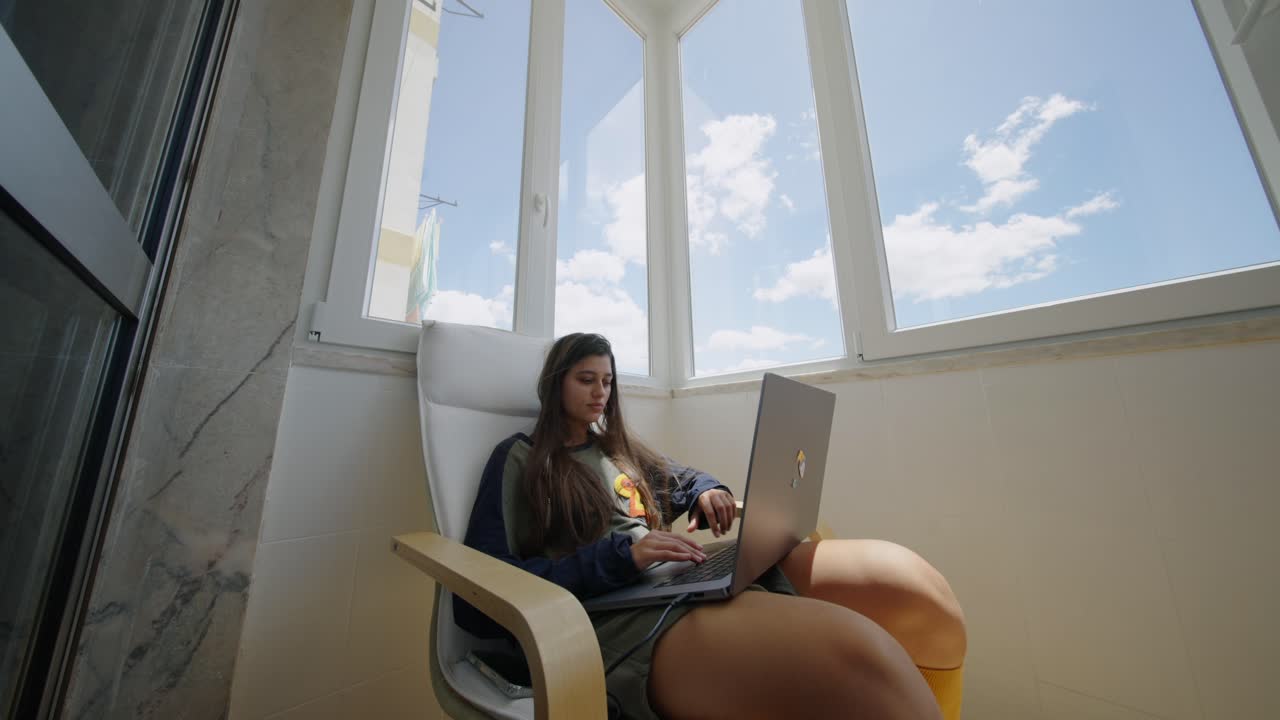 mujer trabajando en una computadora portátil en el balcón