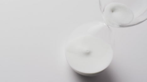 video of hourglass with sand pouring, copy space on white background
