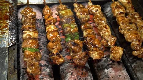 skewers of glazed meat and vegetables grilling outdoors. street food in daejeon, south korea. closeup shot
