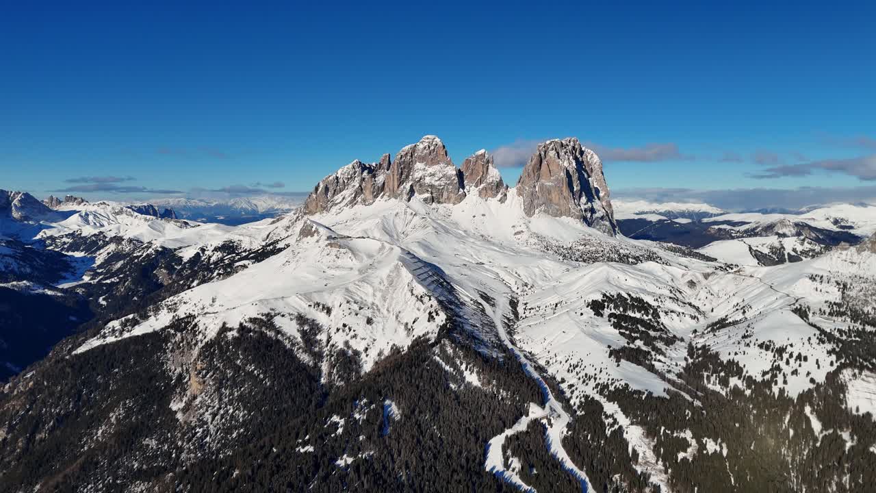 Rock formation in the Italian Dolomites surrounded by incredible landscape covered in snow during winter season on sunny day (drone footage)