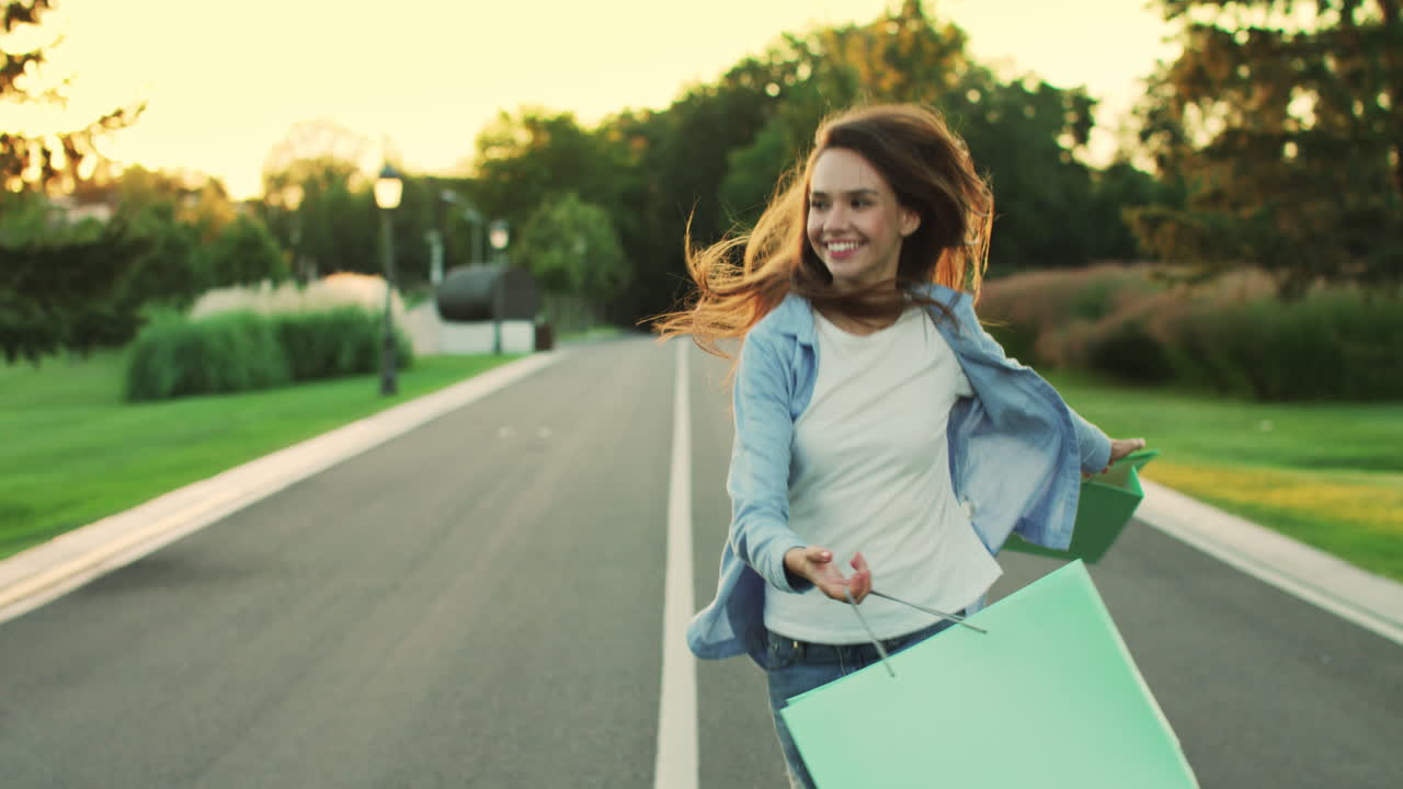 mujer feliz con la compra en la bolsa caminando en el parque de la ciudad. chica feliz