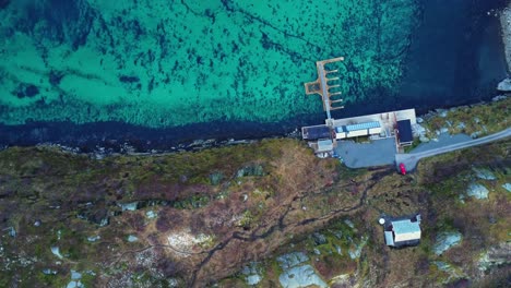 Turquoise-sea-with-rocky-shore-near-asphalt-road-in-Lofoten